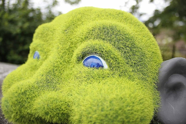 Resin hedge peeker positioned amongst greenery