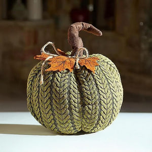 Textured green pumpkin decoration with orange leaves on a blurred background