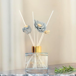 Reed diffuser with floral design on a neutral background