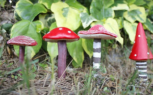 Four red mushroom ornaments displayed in a garden