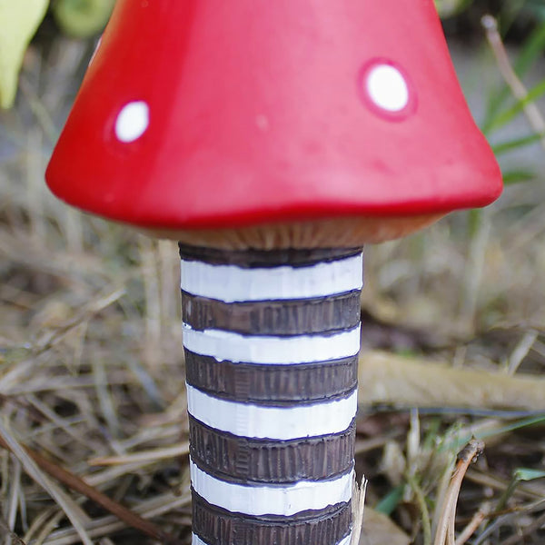 Red resin toadstools displayed inside a plant pot