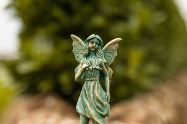 Resin fairy statue positioned in flower bed