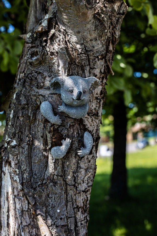 Koala garden decoration peeking around a tree
