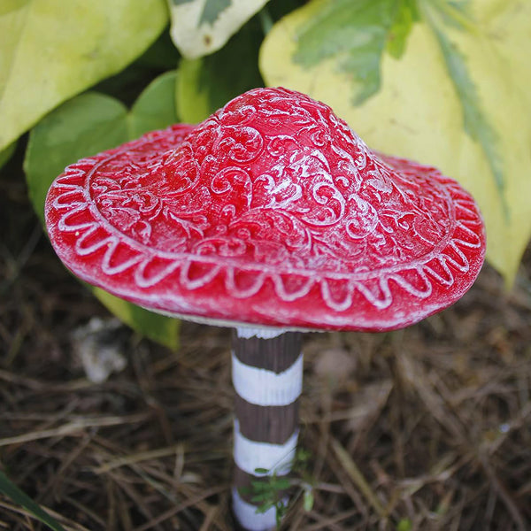 Miniature mushroom decorations positioned beside a garden pond