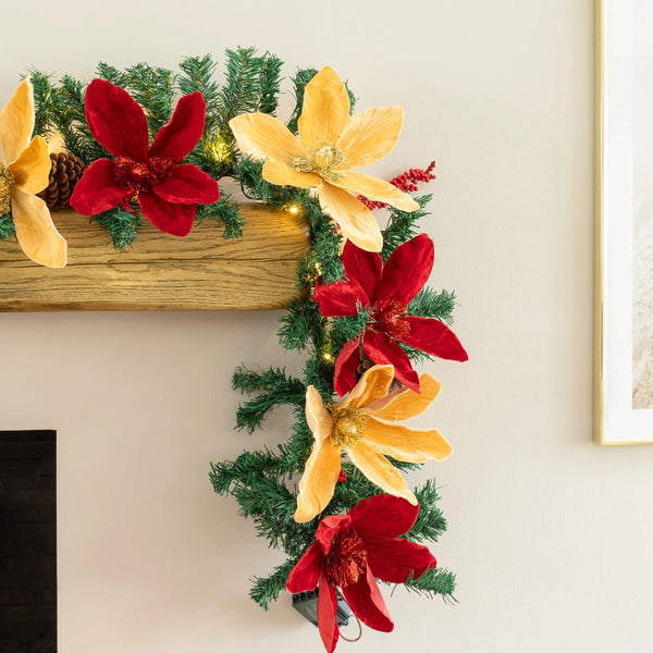 Decorative garland with red and yellow flowers on a mantel.
