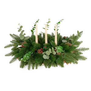 Decorative greenery arrangement with candles on a white background