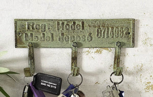 Vintage-style key holder with decorative plate on a textured wall.