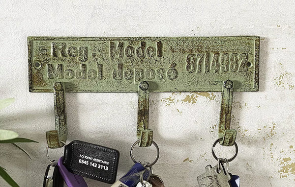 Vintage-style key holder with decorative plate on a textured wall.