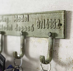 Vintage-style metal key holder with engraved text on a textured wall.
