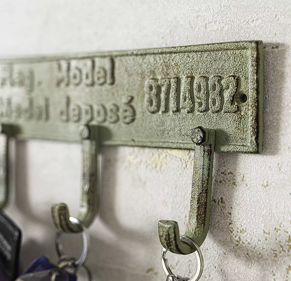 Vintage-style metal key holder with engraved text on a textured wall.