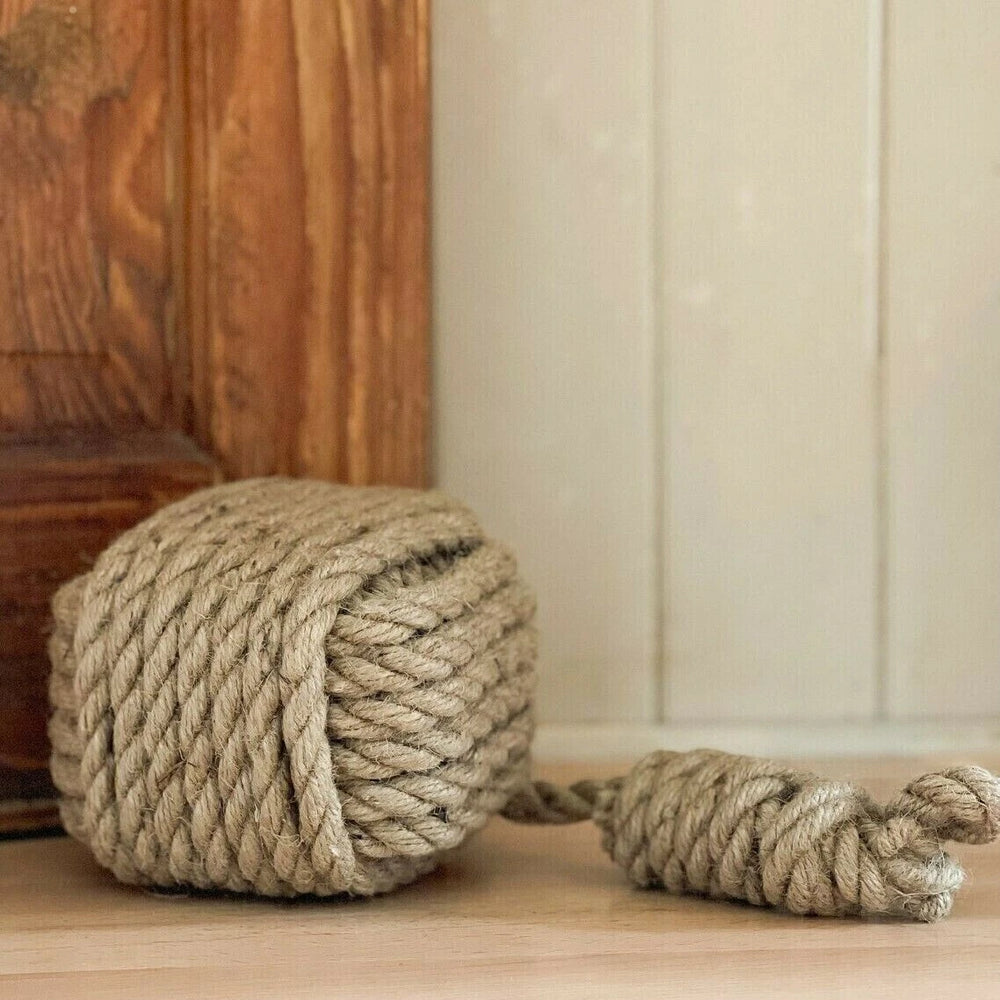 Large ball of rope on a wooden floor with a wooden cabinet in the background.