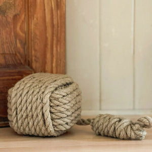Large ball of rope on a wooden floor with a wooden cabinet in the background.