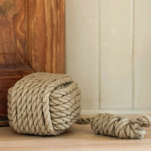 Large ball of rope on a wooden floor with a wooden cabinet in the background.