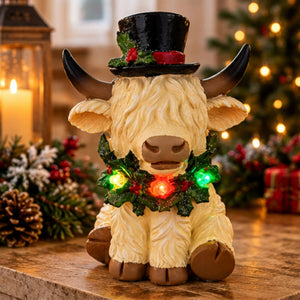 White Highland cow ornament wearing festive top hat with illuminated wreath.