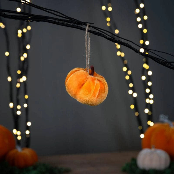 Decorative pumpkin hanging from a string with blurred lights in the background