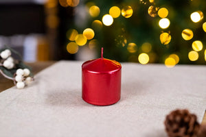 Red candle on a textured surface with blurred festive lights in the background