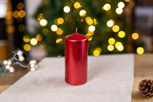 Red candle on a table with a blurred Christmas tree in the background