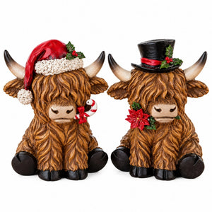 Two decorative Highland cow figurines with brown shaggy fur, black hooves, and curved horns, shown side by side on a white background. The left cow wears a red Santa hat with white trim and a small red-and-white candy cane.