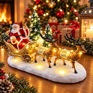 Illuminated Santa sleigh and reindeer ornament on table beside Christmas tree
