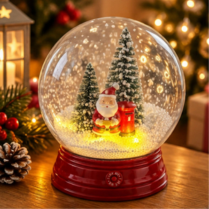 A festive Christmas snow globe with a glowing red base, featuring Santa Claus, miniature trees, and a red mailbox inside a clear globe on a wooden table with warm holiday lights in the background.
