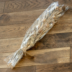 Bouquet of dried flowers in clear plastic wrap on a wooden floor