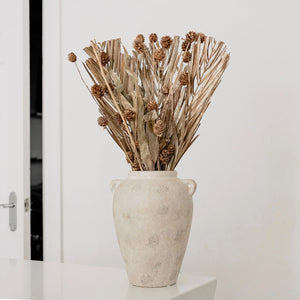 Decorative vase with dried plants on a white surface