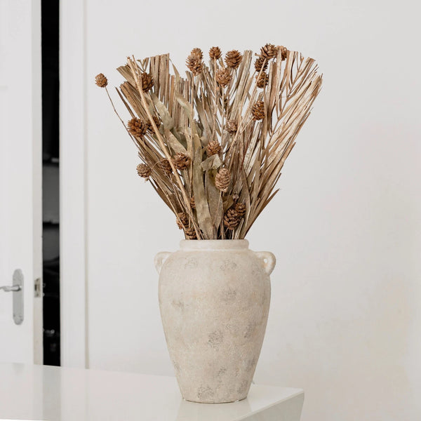 Decorative vase with dried plants on a white surface