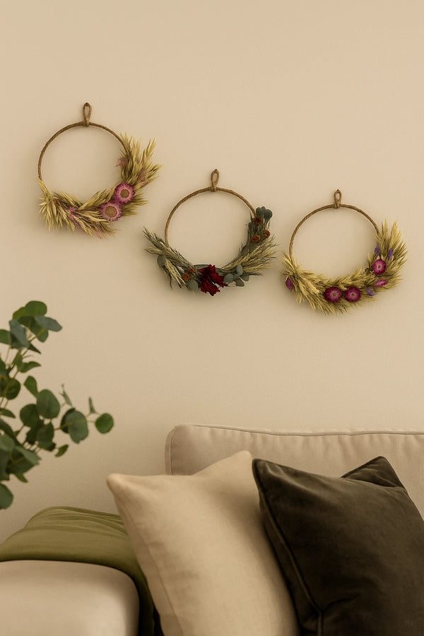 Three decorative wreaths on a wall above a sofa with pillows.