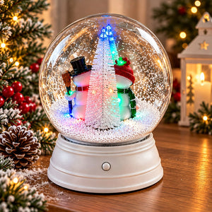 Rear view of snowman snow globe with illuminated snowy Christmas tree.