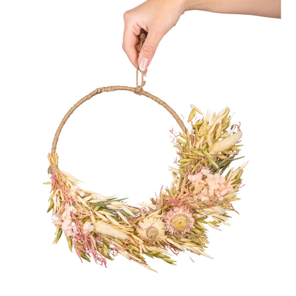 Hand holding a dried flower wreath against a white background