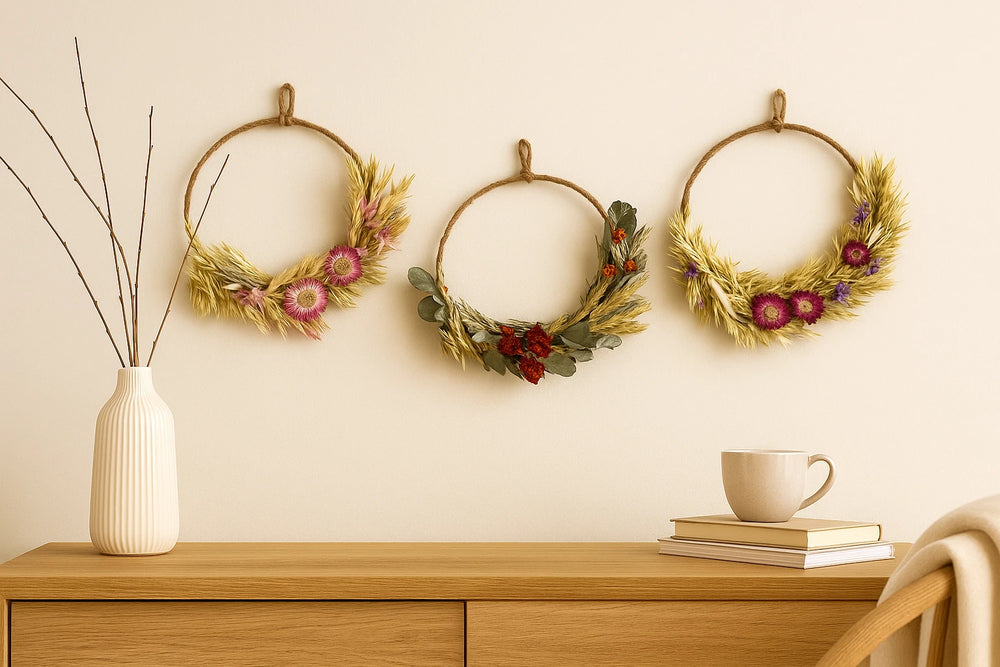 Three decorative wreaths on a wall above a wooden cabinet with a vase and books.