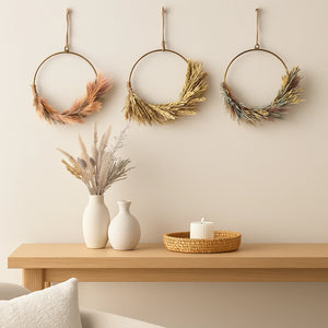Decorative wreaths hanging on a wall above a wooden console table with vases and a candle.