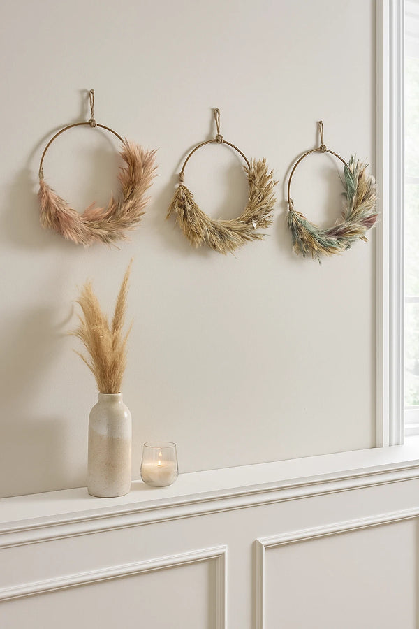 Three decorative wreaths hanging on a wall above a white cabinet.