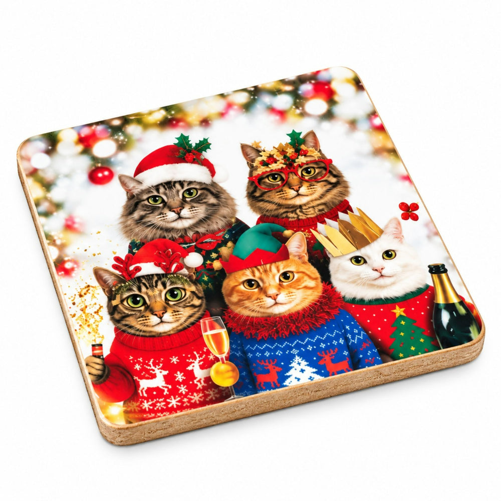 A set of square wooden coasters with a festive Christmas print of four cats in holiday sweaters, shown with one coaster standing in a matching wooden box and another lying flat on a wooden table surrounded by holiday greenery and red ornaments.