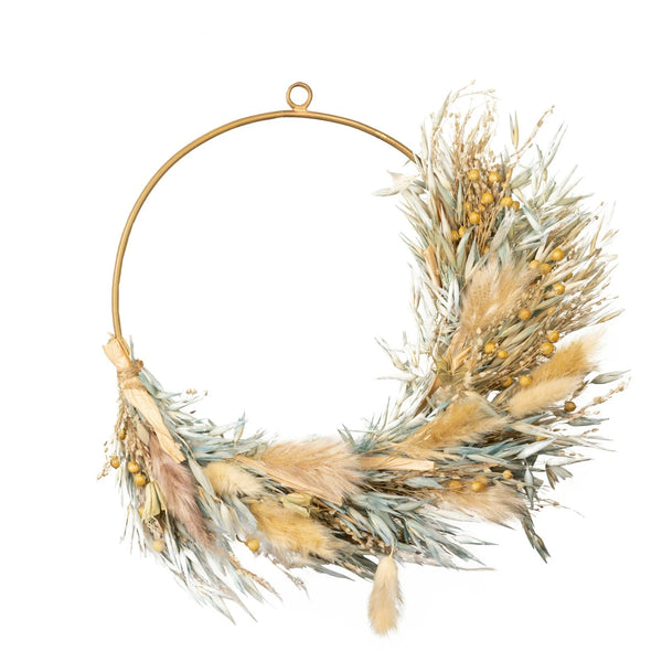 Decorative wreath with dried grasses and gold accents on a white background