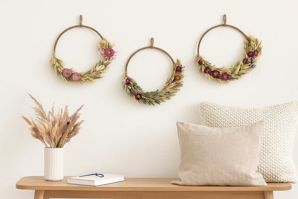 Three decorative wreaths on a wall above a wooden bench with a vase, book, and pillows.