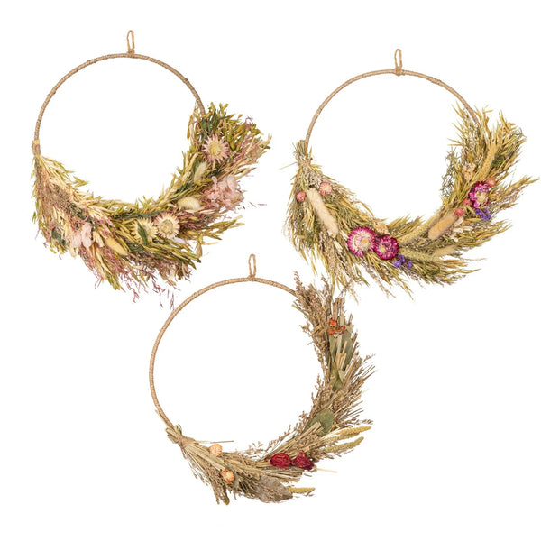 Three circular wreaths made of dried grasses and flowers on a white background