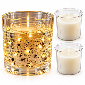 A lit glass candle holder with gold star-shaped glitter and glowing internal lights, shown next to two plain white taper candles in clear holders on a white background.