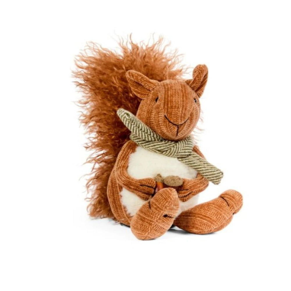 Plush squirrel toy with a scarf on a white surface, surrounded by autumn decorations.