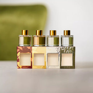 Four perfume bottles with gold caps and a decorative box on a light surface.