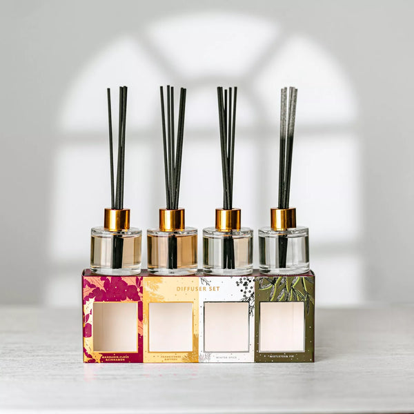 Set of four diffuser bottles with decorative labels on a light background