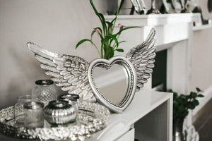 Heart shaped mirror surrounded by angel wings