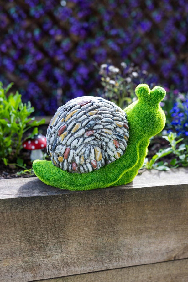 Decorative resin snail positioned in flower bed