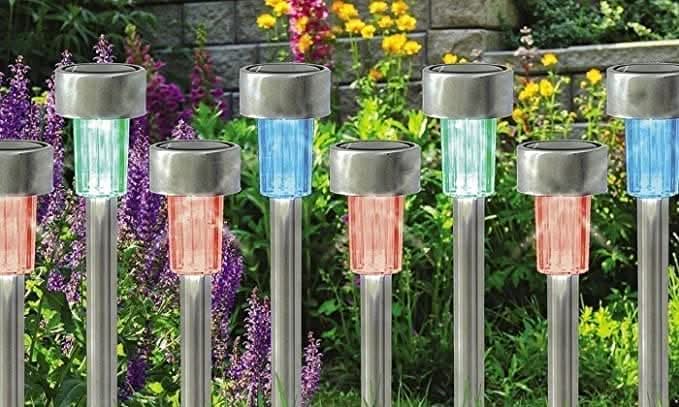 Solar-powered garden lights emitting colorful lights on a grassy area with flowers.