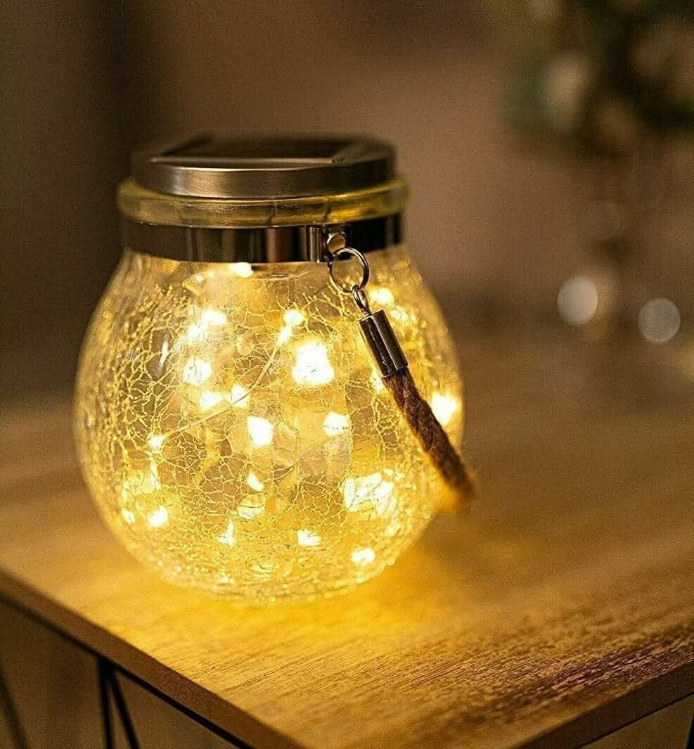 Hanging solar crackle glass lantern glowing in garden at night