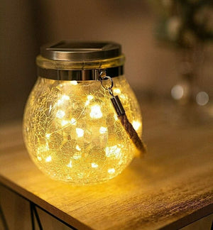 Hanging solar crackle glass lantern glowing in garden at night