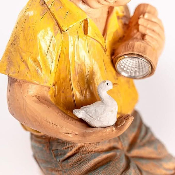 Boy holding a light beside a duck ornament