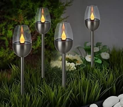 Flame effect solar torch stake lights glowing in garden at night