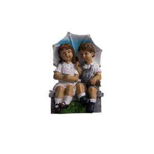Boy and girl garden statue sitting on bench