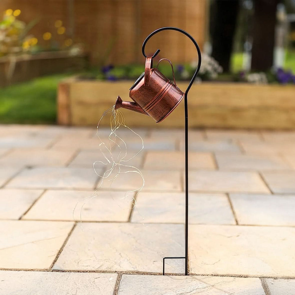 Cascading solar watering can light displayed above flowers